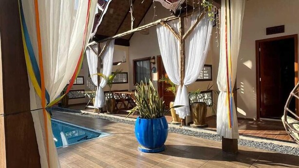 A covered outdoor area with a pool, potted plants, and a wooden ceiling. - Pousada Nosso Canto Alter (Santarém)