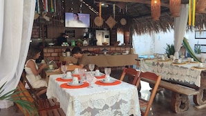 A restaurant with tables set for dining, a bar area, and a poolside area with a hammock. - Pousada Nosso Canto Alter (Santarém)