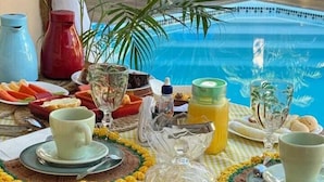A dining table set with plates, glasses, and a fruit bowl, overlooking a pool. - Pousada Nosso Canto Alter (Santarém)