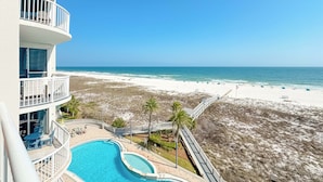 A hotel with a pool, a beach view, and a balcony with outdoor seating. - Spanish Key 407 | Steps from Flora Bama | Pools, Hot Tub, Gym & More! | My Beach Getaways (Pensacola)
