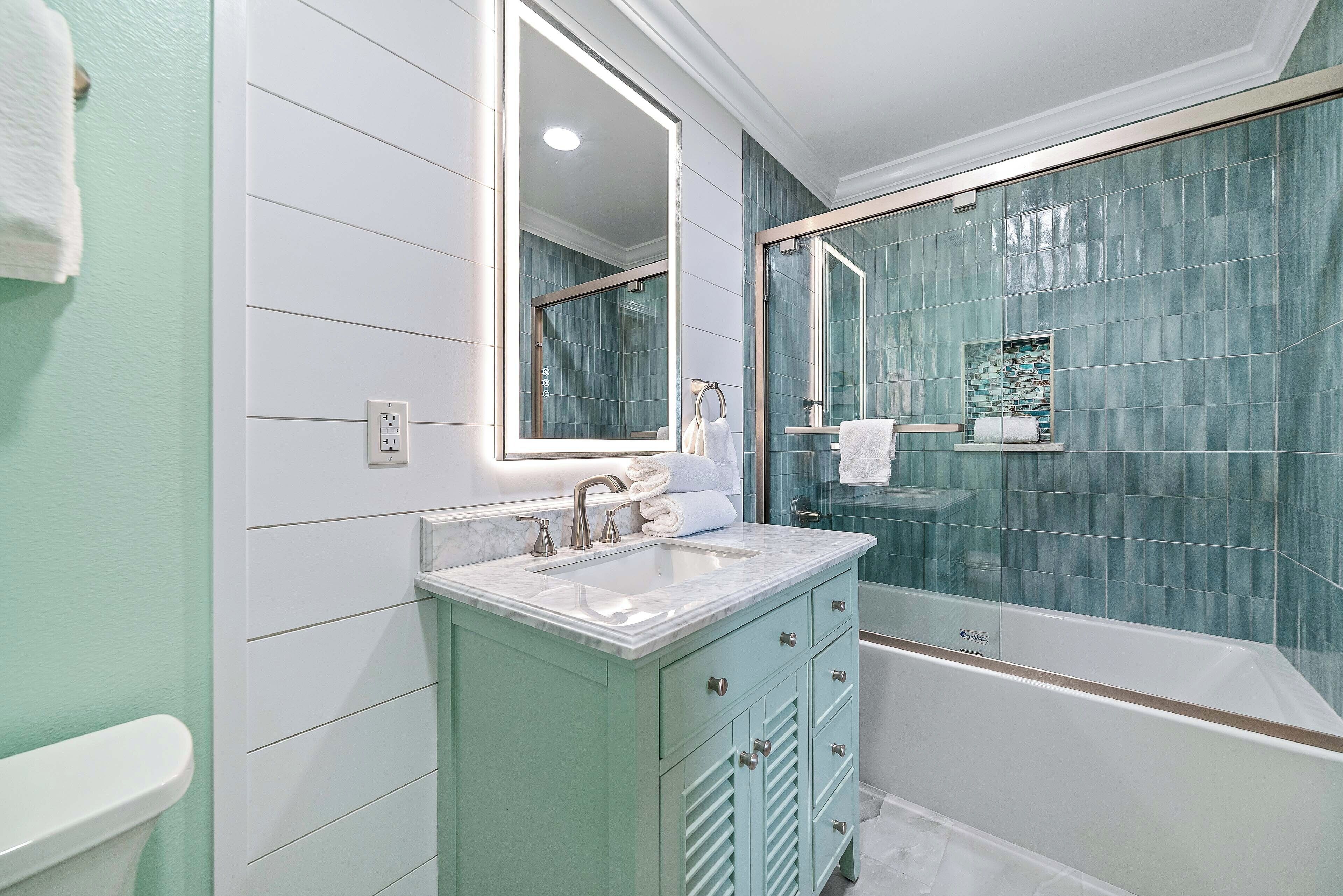 Un baño con lavabo, espejo, tocador y bañera.