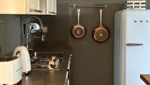 Eine Küche mit einem Herd, zwei weißen Toastern, einem Pendelkocherschrank mit Töpfen und einem weißen Kühlschrank.