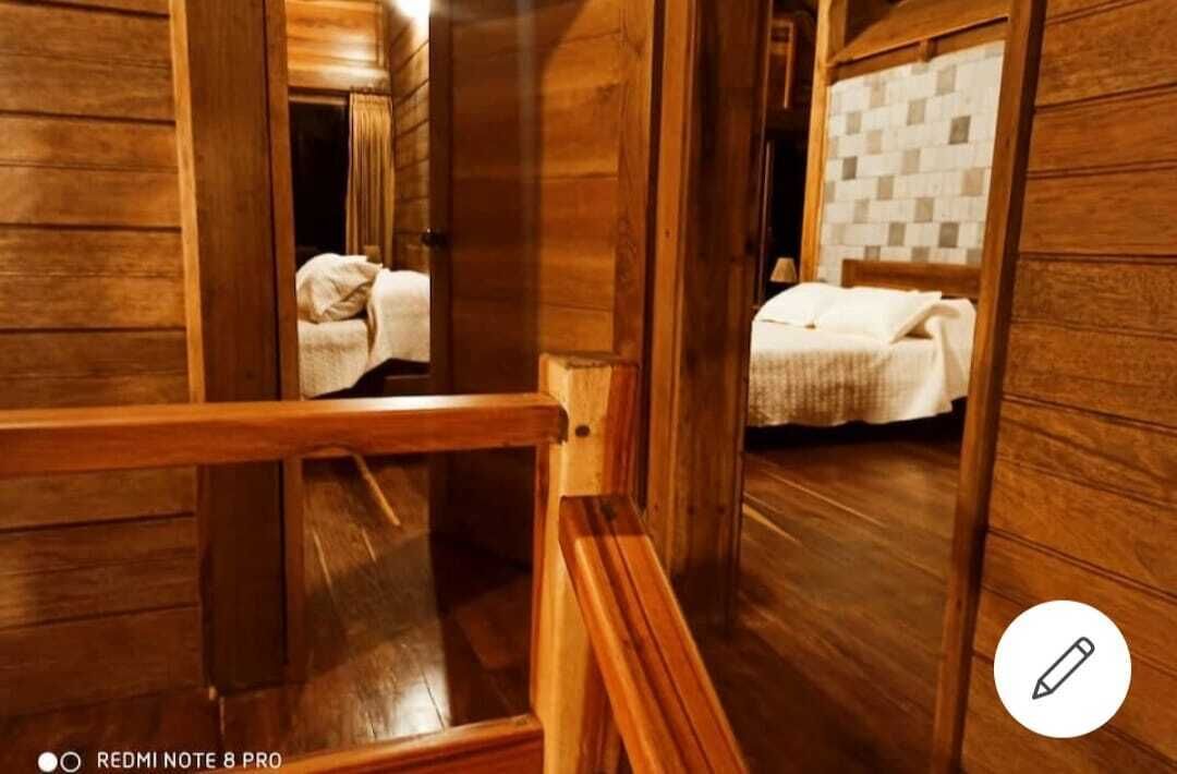 Ein Holzinnenraum mit einem Bett und einem Spiegel, der den Raum widerspiegelt.