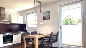 Een moderne keuken met een eethoek, met een houten tafel, stoelen en een koffieapparaat.