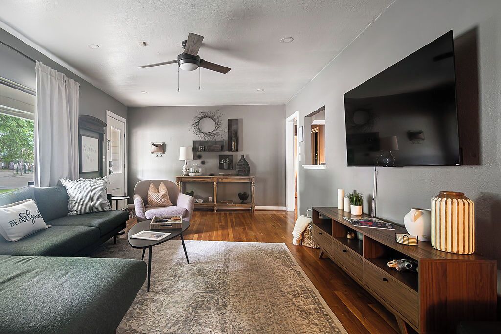 A modern living room with a sofa, armchair, coffee table, TV, and a wooden cabinet.