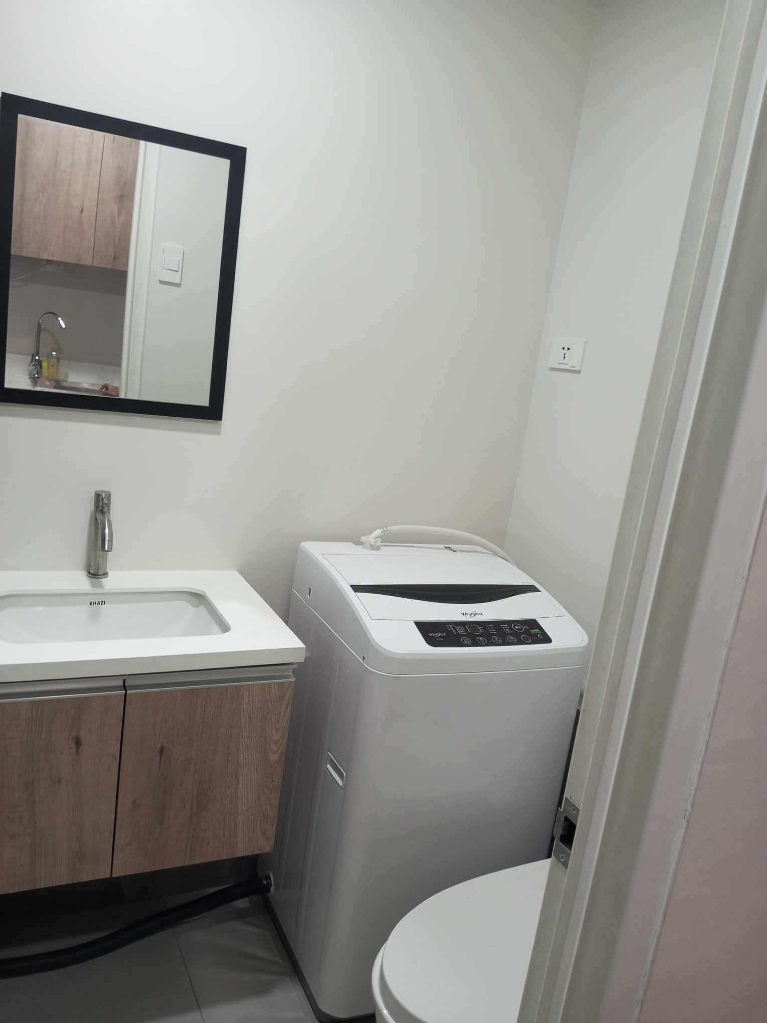 Un baño pequeño con un lavabo blanco, un espejo, un inodoro y una lavadora blanca.