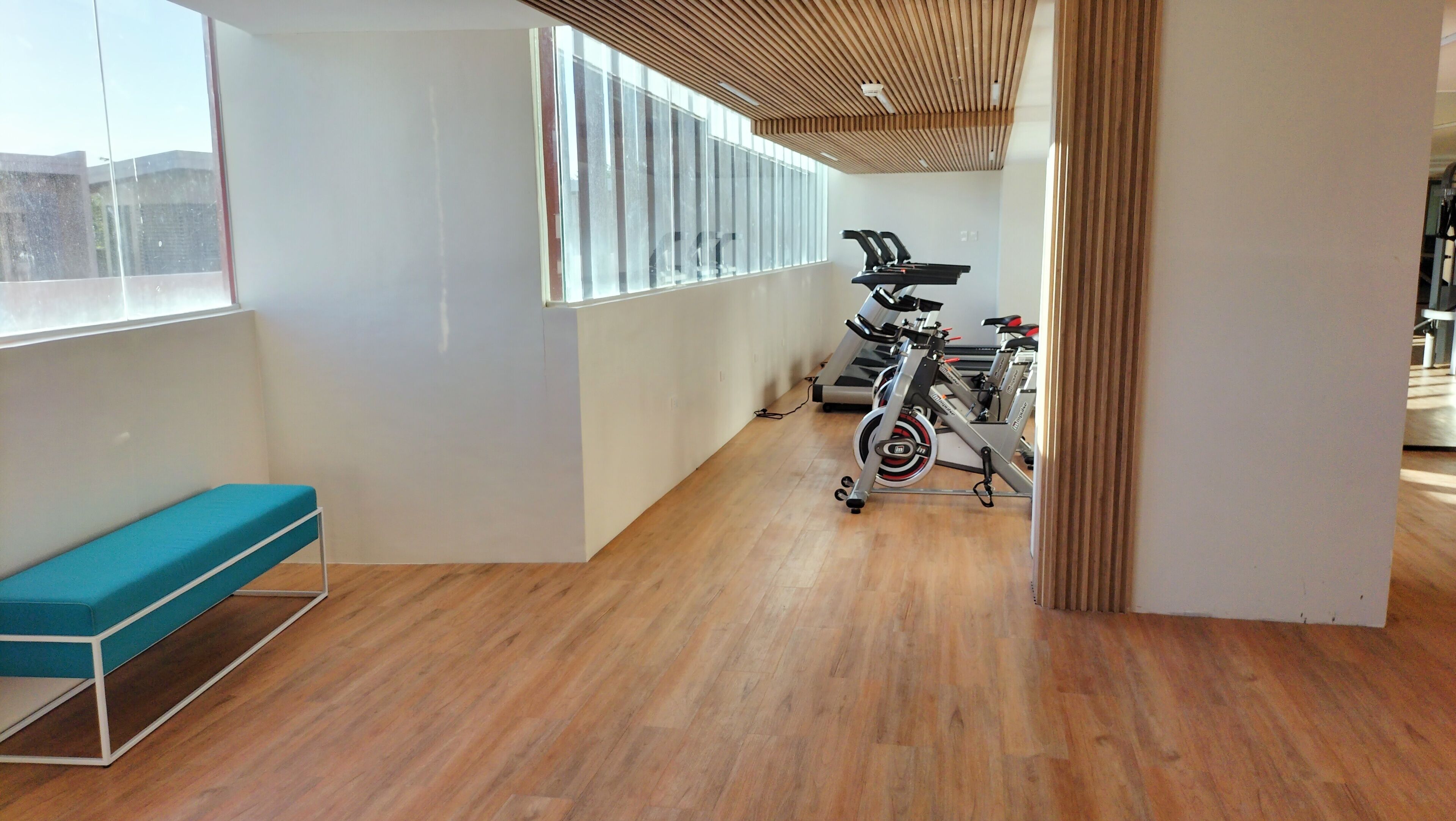 A modern room with wooden flooring, a blue bench, and stationary bikes.