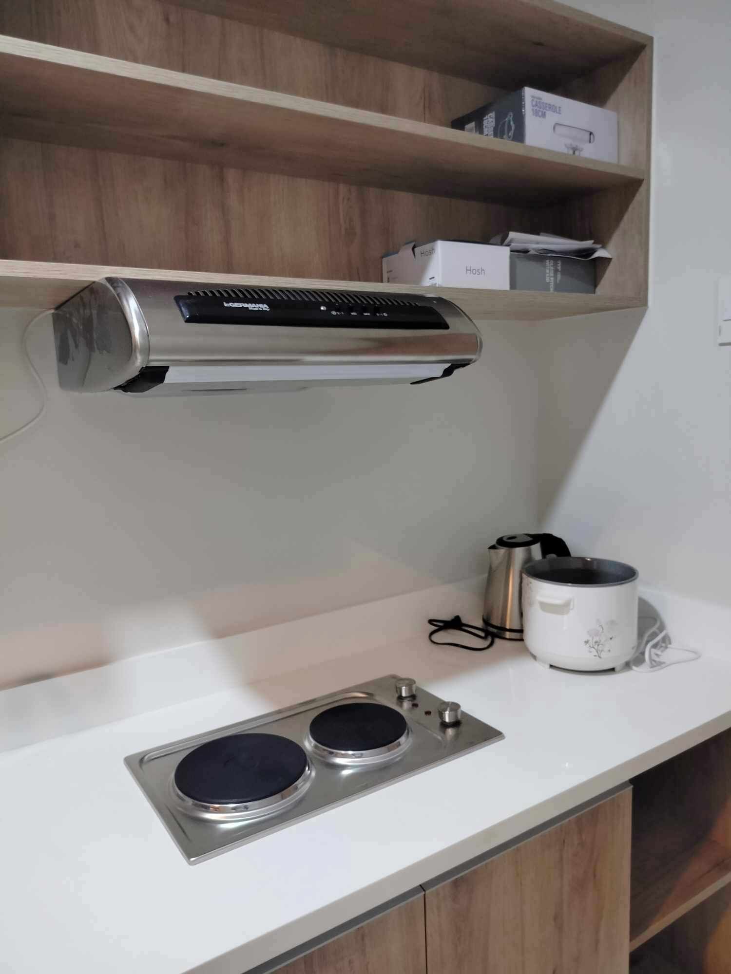 Un espacio kitchenette con estufa integrada, cafetera y estante con cajas.