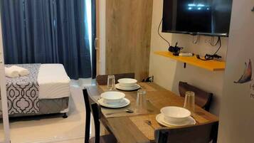 Una camera d'albergo compatta con zona pranzo, un letto, una TV e una parete in legno.