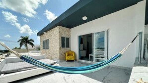 Una hamaca en un patio con una silla amarilla y un edificio moderno al fondo.