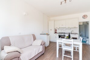 Una cocina moderna con armarios blancos, una mesa de comedor con sillas y un sofá con cojines.