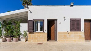 A building with a white facade, a brown door, and a window with brown shutters.