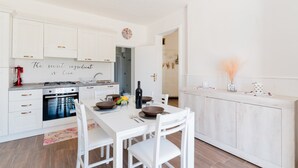A modern kitchen with white cabinetry, a dining table with chairs, and a decorative wall with a quote.