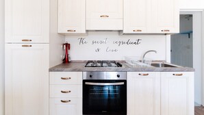 A modern kitchen with white cabinetry, a gas stove, an oven, and a sink.
