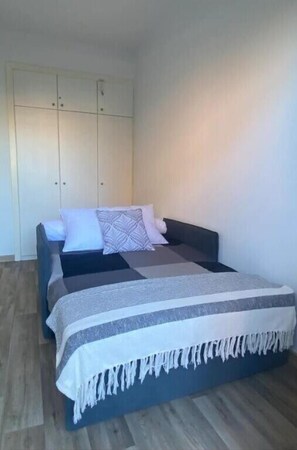 A bedroom with a bed, a wardrobe, and a bedside table.