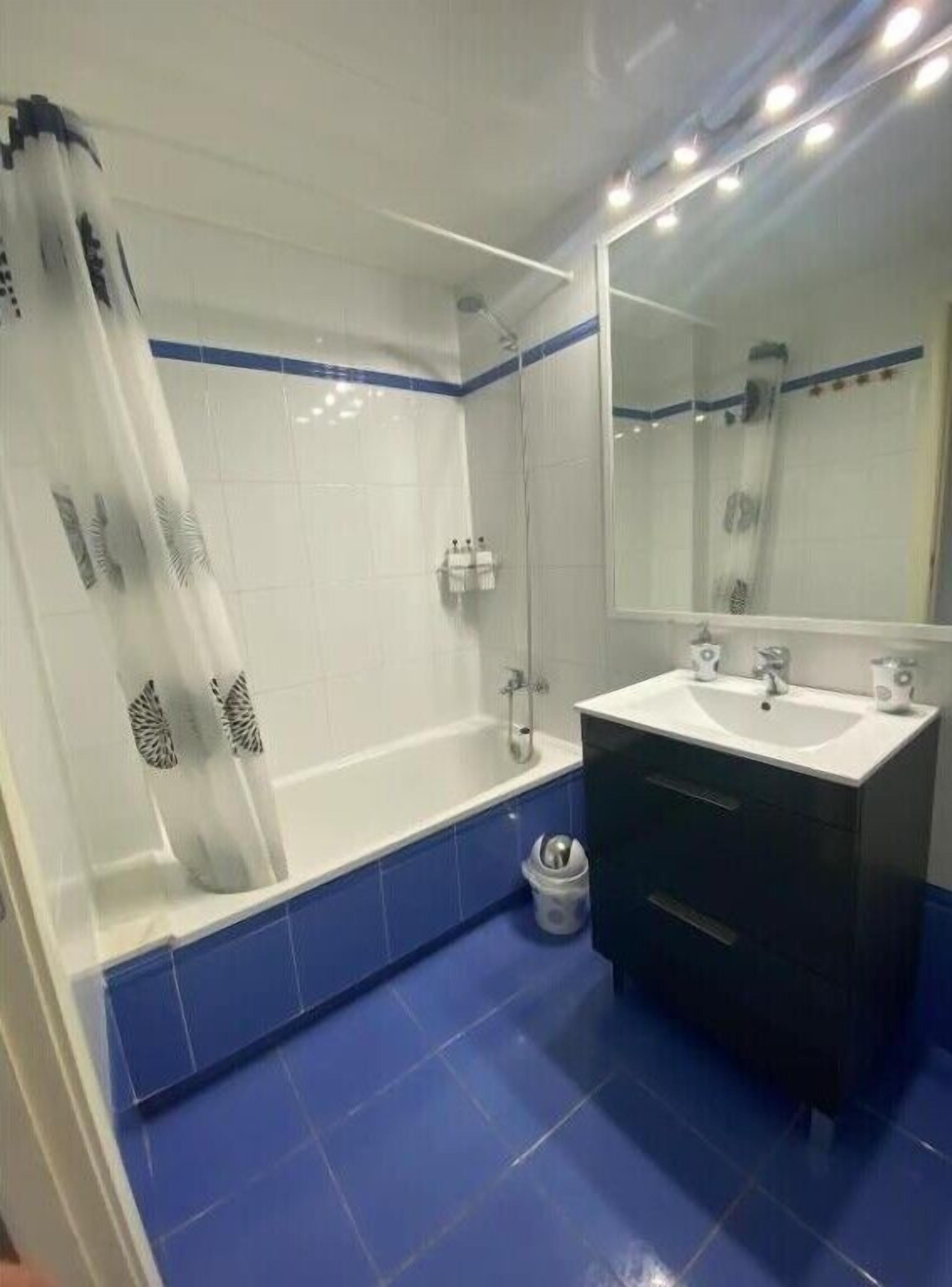 A bathroom with a bathtub, a shower, a sink, and a mirror.