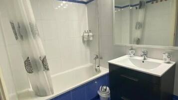 A bathroom with a bathtub, a shower, a sink, and a mirror.