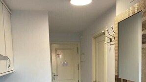 Une petite pièce propre, avec un lavabo blanc, un lave-linge, un miroir et une porte donnant sur une autre pièce.