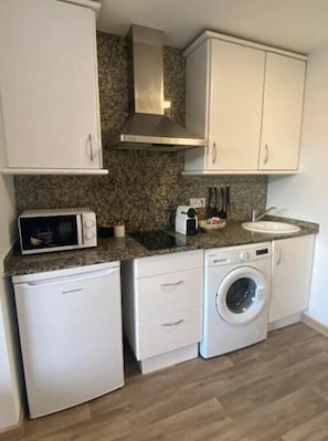A compact kitchen with a microwave, toaster, sink, and washing machine.