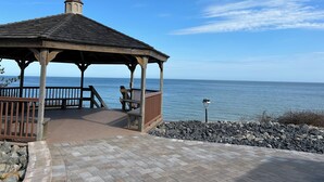 A wooden gazebo with a tiled floor, overlooking a body of water.