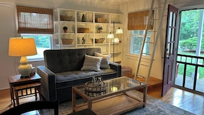 A living room with a sofa, coffee table, and shelves with baskets and decorative items.