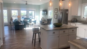 A spacious kitchen with a large island, white cabinetry, and pendant lighting.