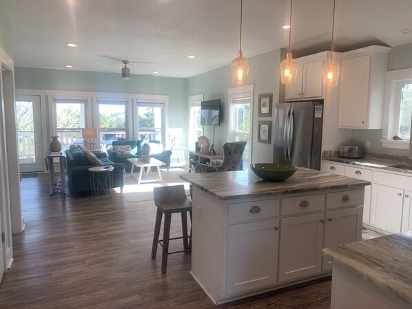 A spacious kitchen with a large island, white cabinetry, and pendant lighting.