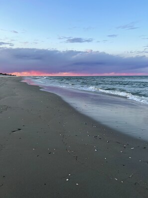 A beach with a wide sandy shore and gentle waves.