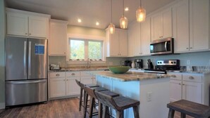 A modern kitchen with white cabinets, stainless steel appliances, and a large island with bar stools.
