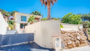 Una propiedad residencial con entrada protegida por portón, una escalera y un muro de contención de piedra.