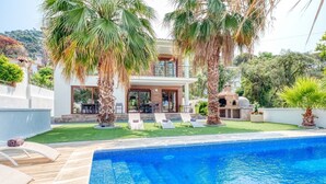 A modern house with a swimming pool, palm trees, and a barbecue area. - Villa "Costacabana - Marcella" with Private Pool, Private Terrace & Wi-Fi (Lloret de Mar)