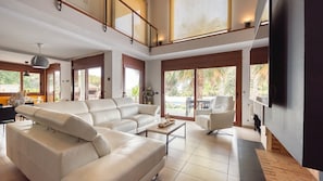 Un salón espacioso con un sofá modular grande, una mesa de centro y un televisor montado en la pared.