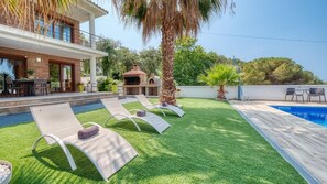 Una casa moderna con piscina, zona de estar exterior y área de barbacoa.