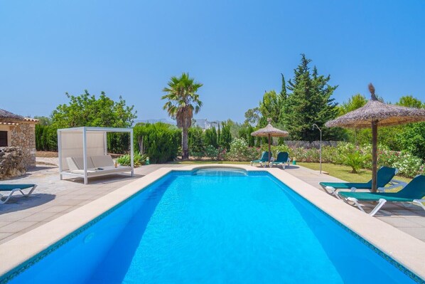 A swimming pool with lounge chairs and a covered seating area.