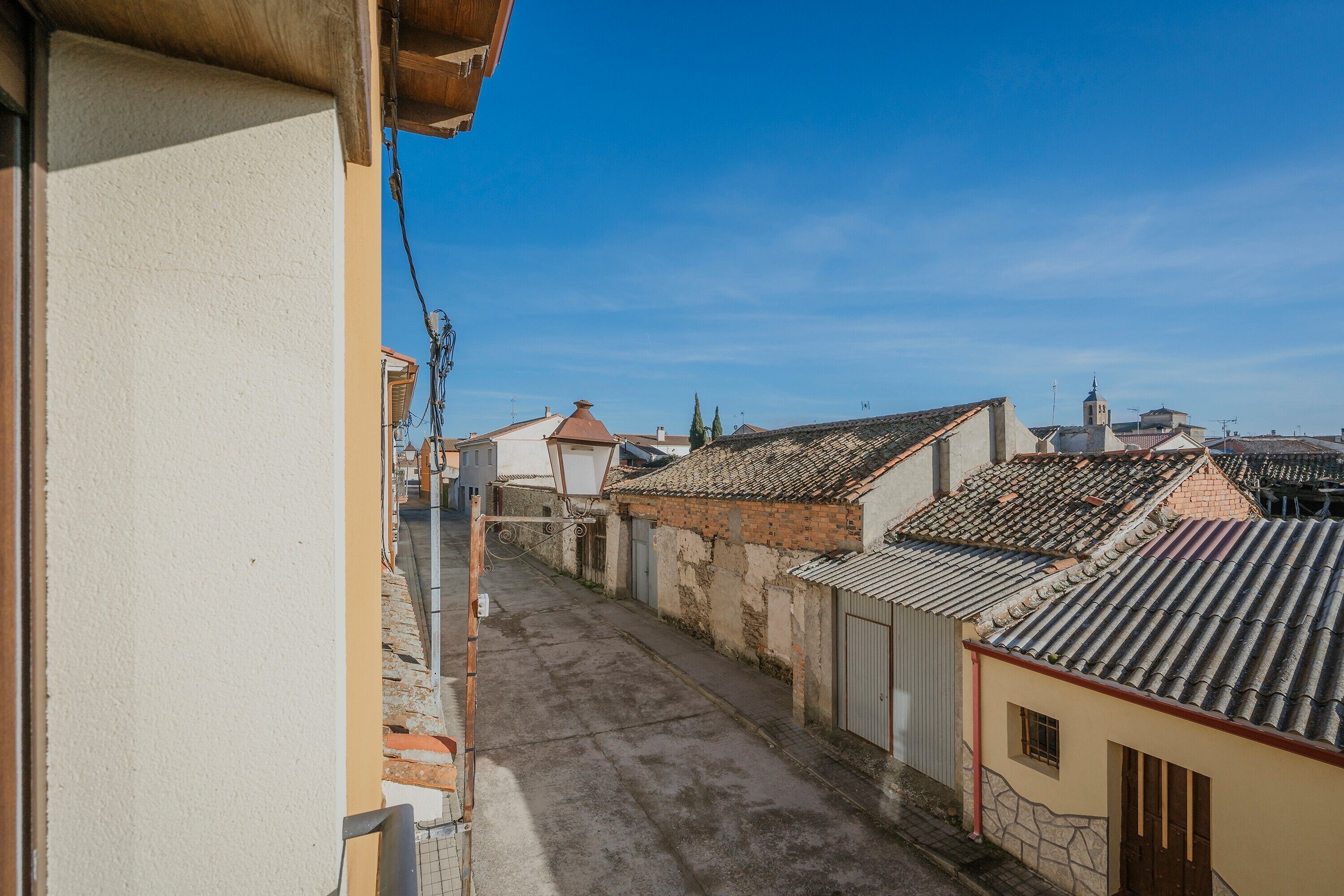 Een smalle straat met traditionele gebouwen, heldere lucht en een zichtbare kerktoren.