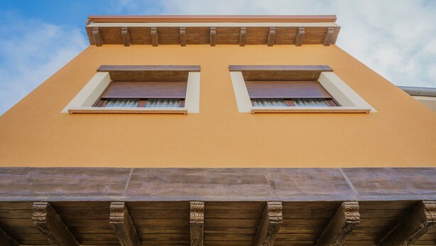 A building with a yellow facade, two windows with shutters, and a wooden beam structure. - Tradition Rural El Tío Ricardo Country House – Private Pool & Garden in Segovia (NIEVA)
