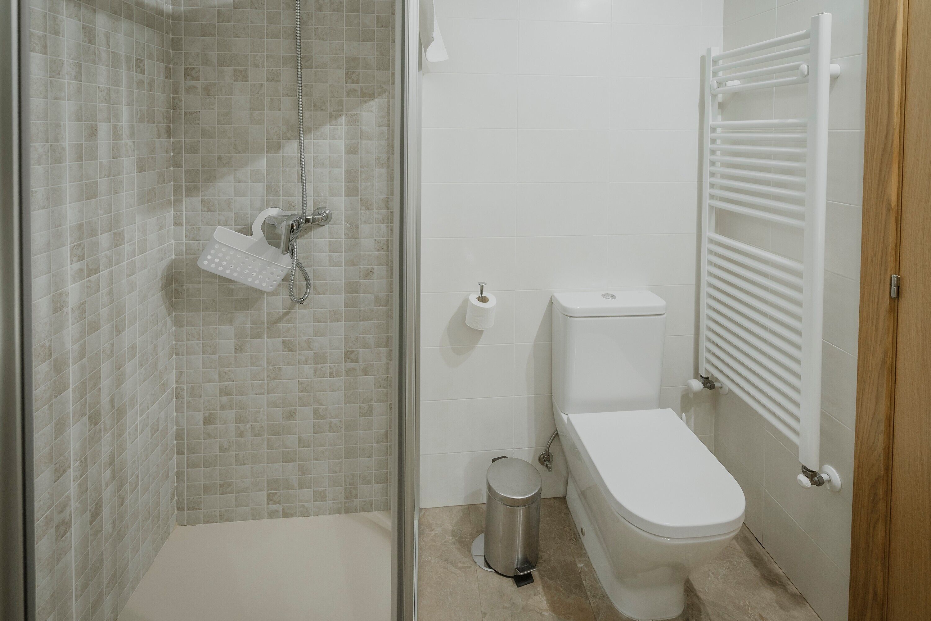 Een badkamer met douche, toilet en een handdoekhouder.