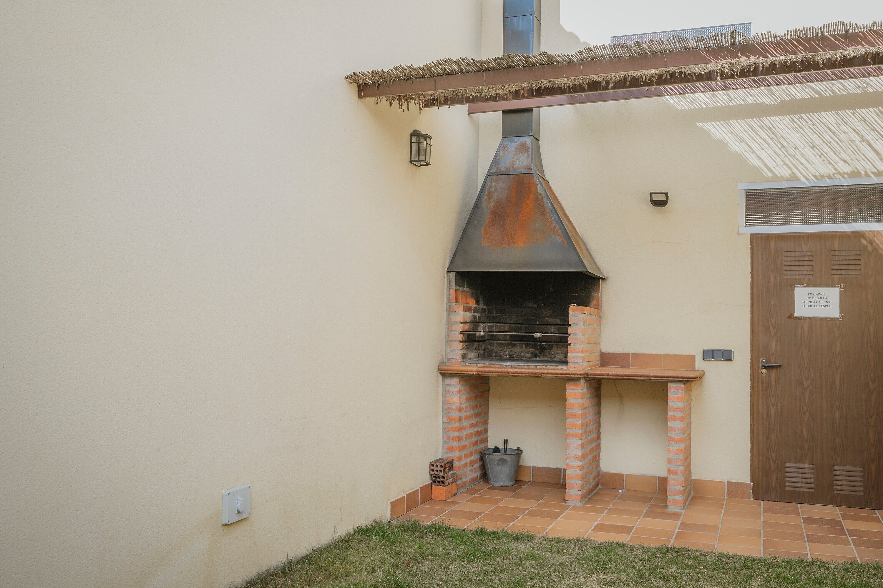 Una parrilla de ladrillo al aire libre con chimenea, una puerta y una pequeña mesa.