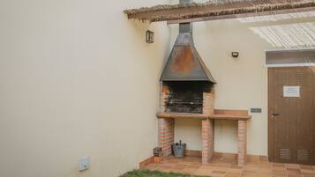 Una parrilla de ladrillo al aire libre con chimenea, una puerta y una pequeña mesa.