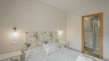Une chambre à coucher comprenant un lit, des tables de chevet, un miroir et un espace douche.