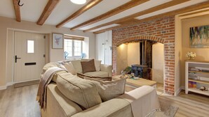 Una sala de estar acogedora con chimenea de ladrillo, vigas de madera y un sofá con una manta.