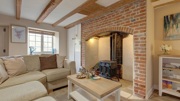 Un salón acogedor con chimenea de ladrillo, un sofá, una mesa de centro de madera y una estantería.