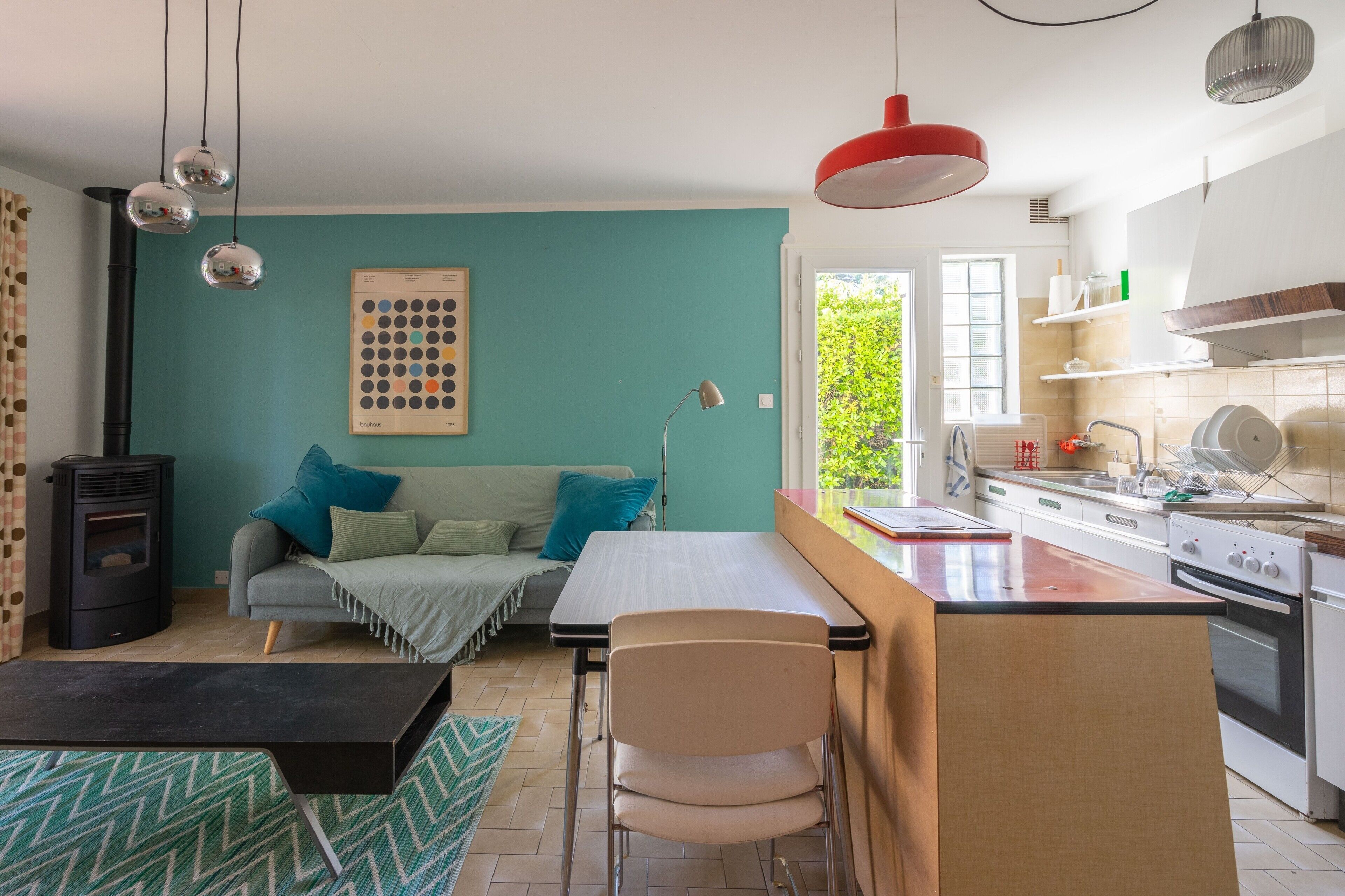 A compact living space with a kitchenette, a sofa, a dining table, and a small stove.