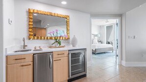 A modern kitchen with a stainless steel refrigerator, wooden cabinets, and a white countertop. - Newly Remodeled Two Bedroom Condo with Immaculate Pool and Bay Views (Orange Beach)