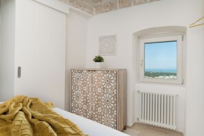 A bedroom with a bed, a decorative screen, a window with a view, and a radiator. - Terrazza Ariafina by Wonderful Italy (Ostuni)