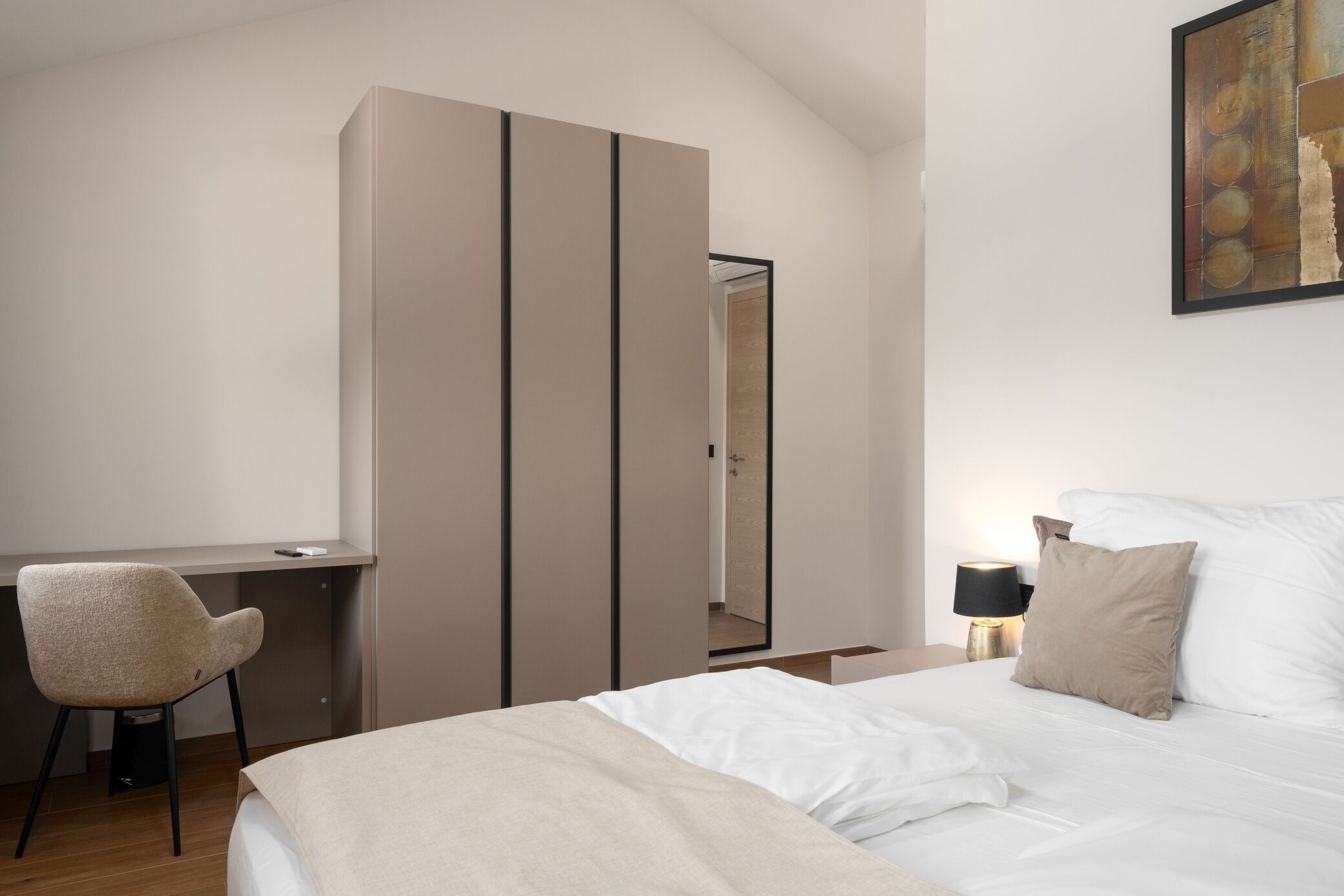 A modern bedroom with a bed, a desk, and a chair.