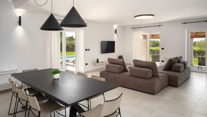 Una sala moderna con una mesa de comedor de madera oscura, sillas color beige y un sofá seccional marrón.