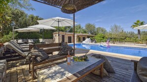Un espace aménagé au bord de la piscine, avec des chaises longues, des parasols et une piscine.