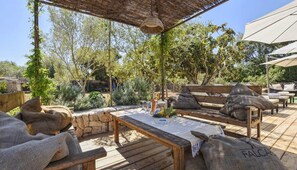 Une terrasse extérieure avec des meubles en bois, un plafond en osier et des murs en pierre.