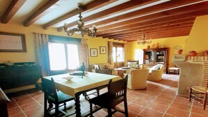 Un comedor con una mesa y sillas, una cocina con estufa y armarios, y una sala de estar con sofá y chimenea.